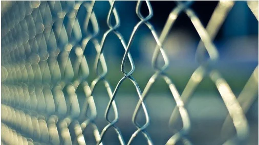 Close-up of a chain-link fence with a blurred background, symbolizing security and protection.